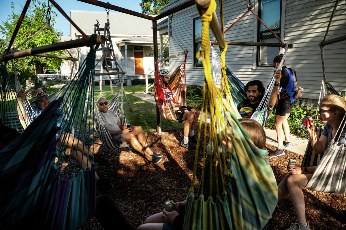 Members of a local bicycle club relax in hammocks at The Plant House, a renovated 1890s house and AirBnB rental in the heart of Concept Neighborhood's development project in the Second Ward, on Saturday, November 5, 2022 in Houston, Texas. The developers aim to design several blocks in a socially conscious way that is pedestrian and bike-friendly and uplifts local residents and small businesses. 