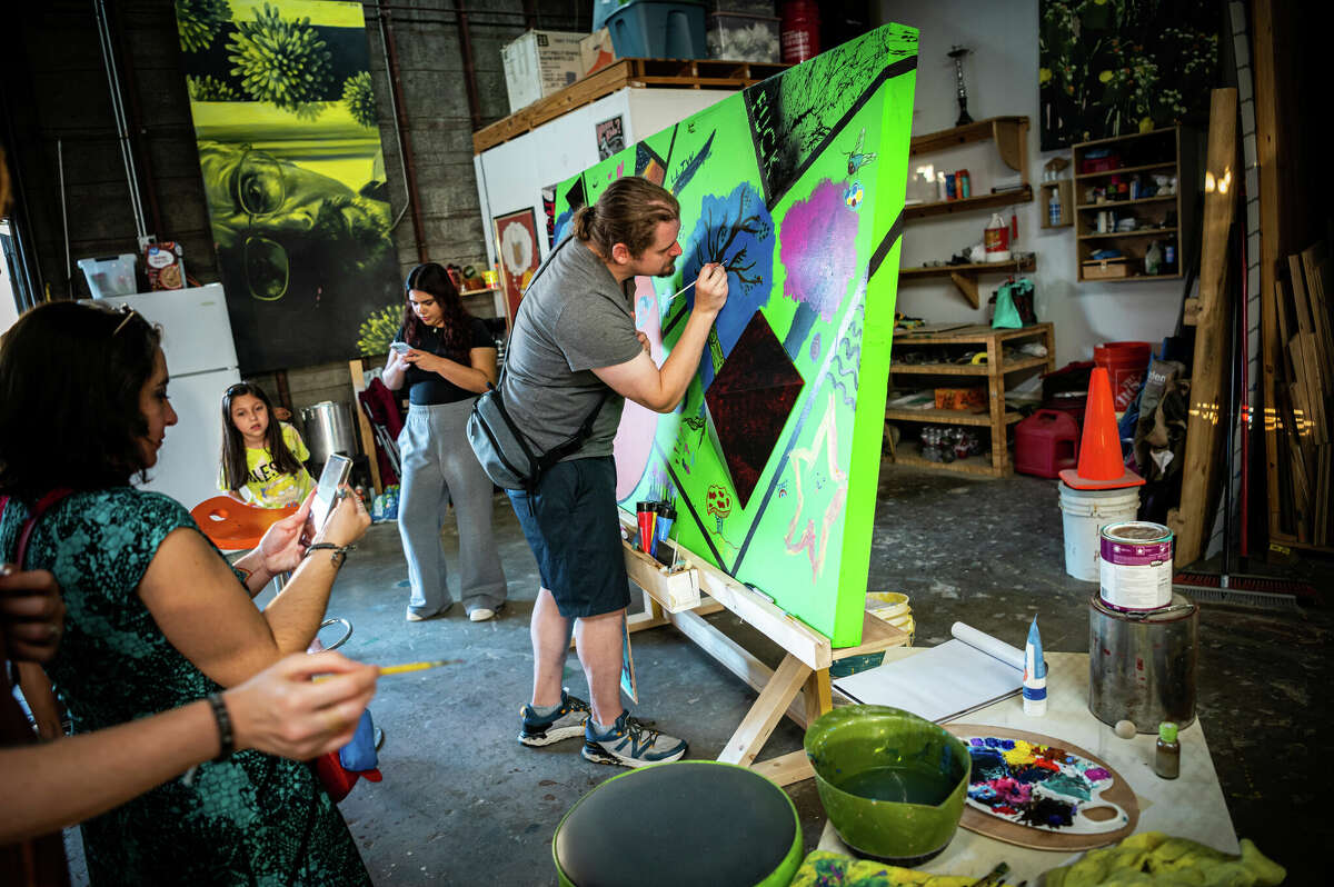 Blake Stell, 38, paints a crow on a collaborative mural during a block party in the Second Ward in Houston, Texas on Saturday, November 5, 2022. 