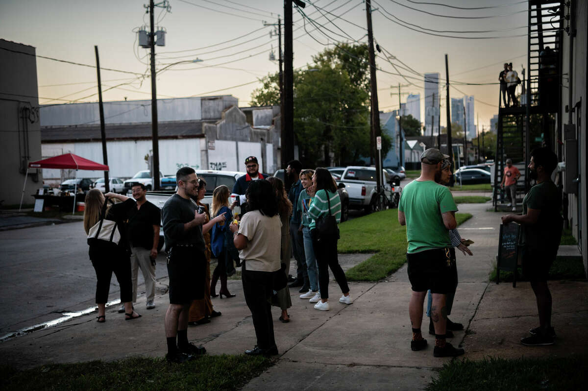 People hang out outside of an old warehouse, owned by Concept Neighborhood during a block party in the Second Ward in Houston, Texas on Saturday, November 5, 2022. Concept Neighborhood plans to rent the property as a creative or retail space, as part of their project to redevelop several blocks in the Second Ward in a socially conscious way that is pedestrian and bike-friendly and uplifts local residents and small businesses.