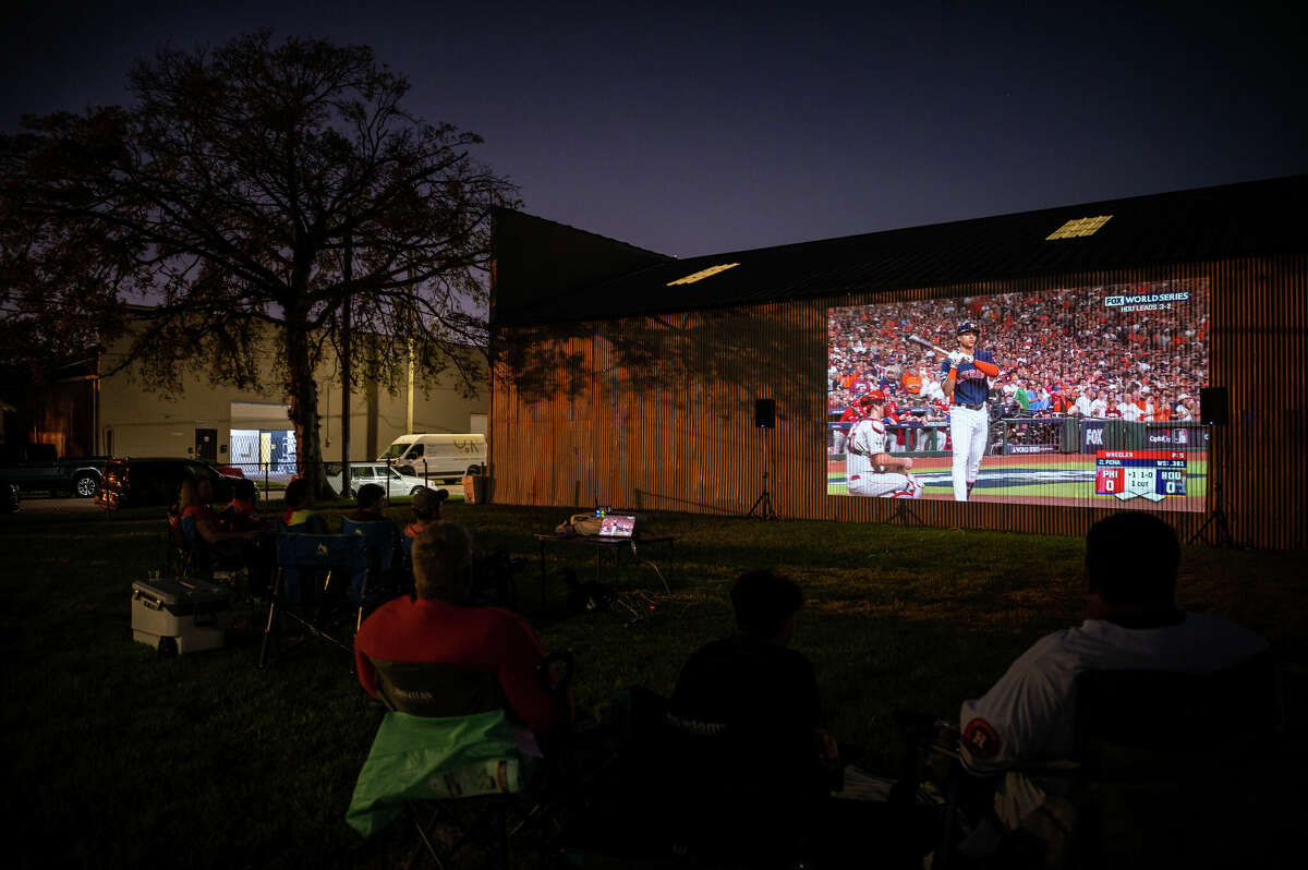 People watch the Astros play in the sixth game of the World Series, projected onto the side of an old warehouse that is owned by Concept Neighborhood, during a block party in the Second Ward in Houston, Texas on Saturday, November 5, 2022. Concept Neighborhood plans to rent the property as a creative or retail space, as part of their project to redevelop several blocks in the Second Ward in a socially conscious way that is pedestrian and bike-friendly and uplifts local residents and small businesses. 