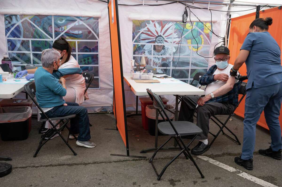 Maria (left) and Faustino Salazar recieve coronavirus booster shots at the Unidos en Salud clinic in San Francisco's Mission District. Health officials are encouraging people to get the new updated booster shot as uptake continues to flag.