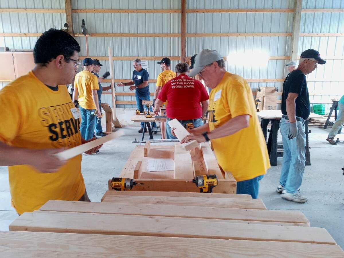 Volunteers use tools and materials provided by Sleep in Heavenly Peace to build beds for children in need.