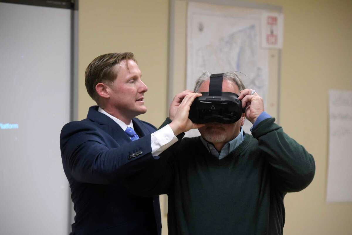 Mayor Dean Esposito puts connected  a VR headset with assistance   from Clint Collins, VR Subject Matter Specialist, with Axon during a presumption    of their VR, virtual reality, grooming  to the Danbury Police Department connected  Thursday morning. It included taser simulator technology. November 17, 2022, Danbury, Conn.