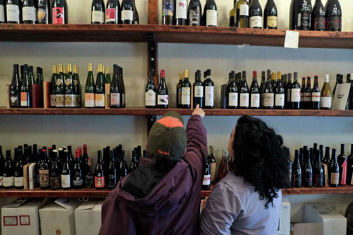 Dorrie Mazzone points to a bottle at Ordinaire in Oakland, which will be open on Thanksgiving from 11 a.m. to 3 p.m.