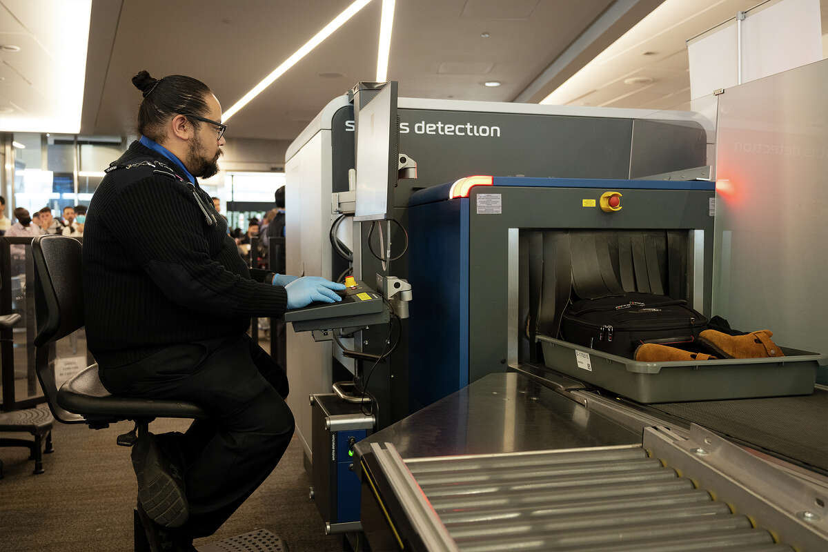 An SFO officer checks hand luggage at SFO on November 16, 2022