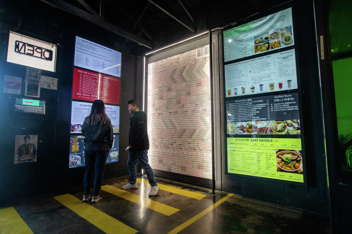 Two customers look at the menu board before ordering at The Night Market in South San Francisco, California on November 10, 2022.