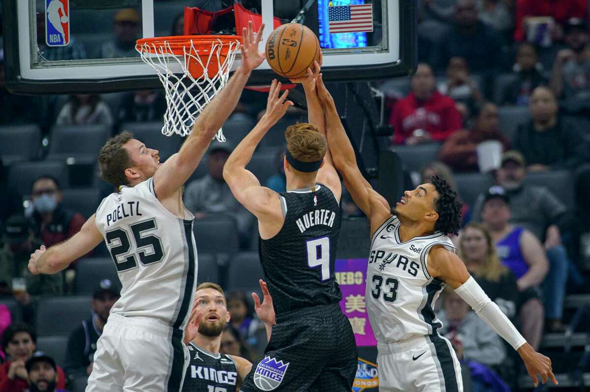 Sacramento Kings guard Kevin Huerter (9) shoots over San Antonio Spurs center Jakob Poeltl (25) and Spurs guard Tre Jones (33) during the first quarter of an NBA basketball game in Sacramento, Calif., Thursday, Nov. 17, 2022.