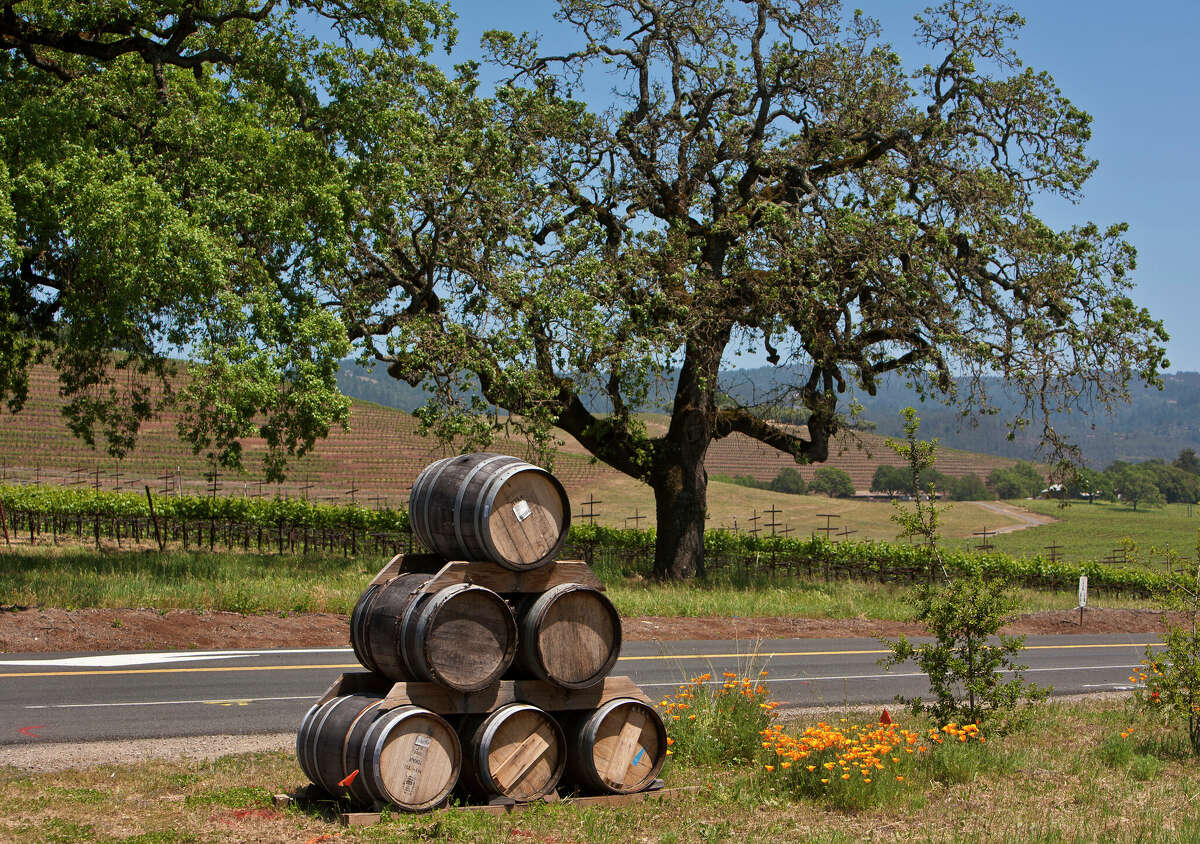 A stack of wine barrels sits on the side of the road near the entrance to Deerfield Ranch Winery in Kenwood, California.
