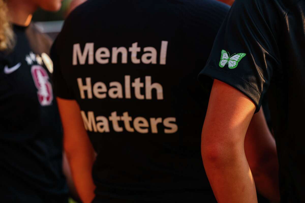 The Stanford women’s soccer team dons warmup jerseys with “Mental Health Matters” on their backs as well as a green butterfly patch on their sleeves to remember late goalie Katie Meyers earlier this year.