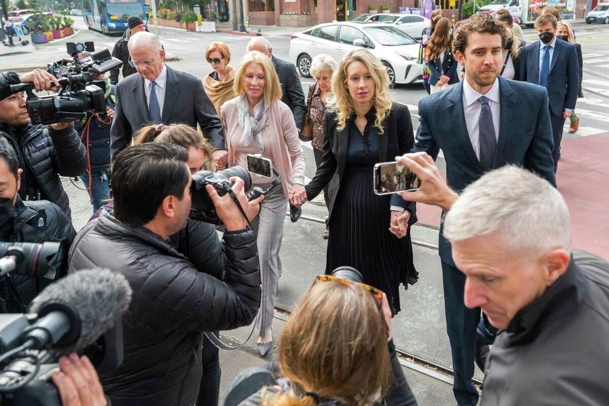 Theranos founder and CEO Elizabeth Holmes, center, walks into federal court with her partner Billy Evans, right, and her parents in San Jose, Calif., Friday, Nov. 18, 2022. A federal judge will decide whether Holmes should serve a lengthy prison sentence for duping investors and endangering patients while peddling a bogus blood-testing technology.
