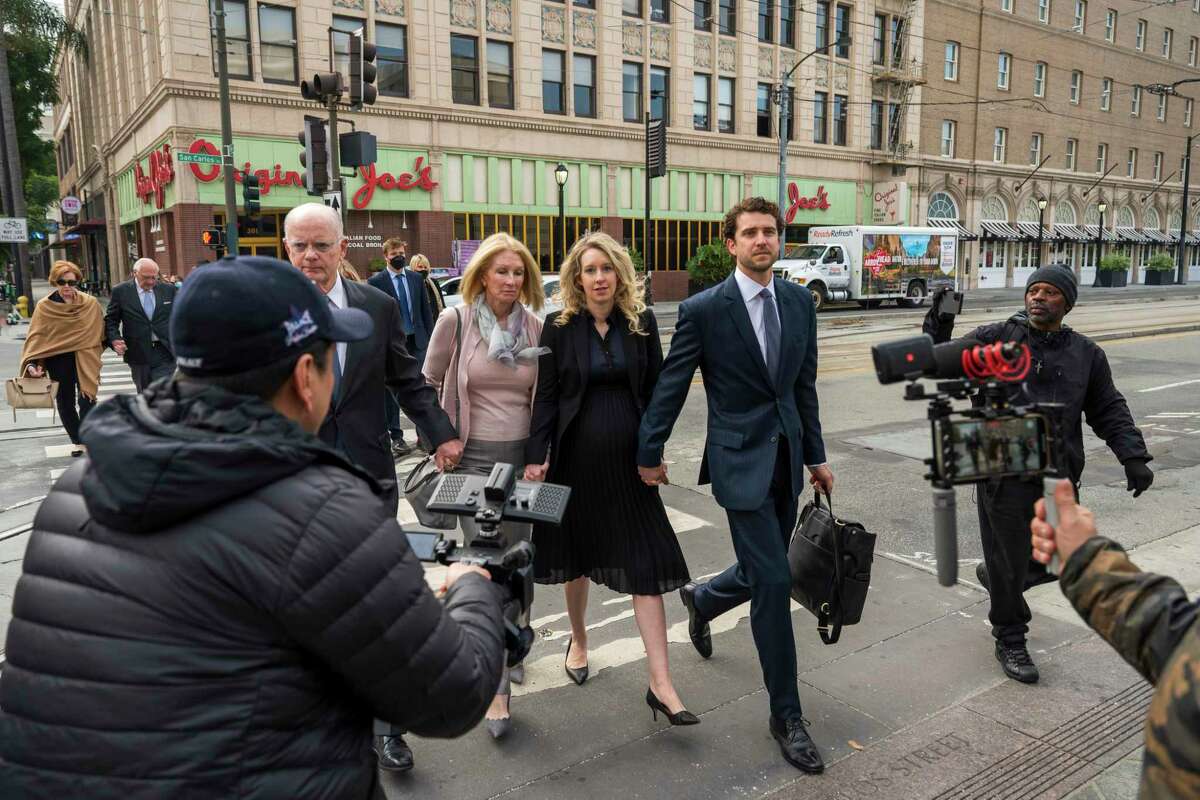 Theranos founder and CEO Elizabeth Holmes, center, walks into federal court with her partner Billy Evans (right) and her parents in San Jose, Calif., Friday, Nov. 18, 2022. A federal judge will decide whether Holmes should serve a lengthy prison sentence for duping investors and endangering patients while peddling a bogus blood-testing technology.