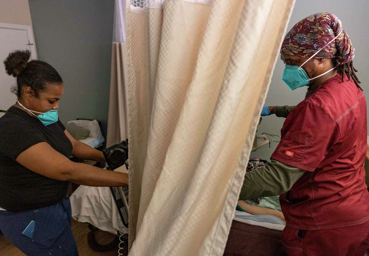 Two certified nurse assistants, Ten Iqua, left, and Okeibunov Iweze transfer a resident back to her bed at Focused Care at Waxahachie in Waxahachie earlier this year. Texas does not have enough nurses for its senior care facilities. Compared with 2019, there is an 18 percent decrease in registered nurses employed in Texas nursing facilities, according to data from the U.S. Bureau of Labor Statistics.