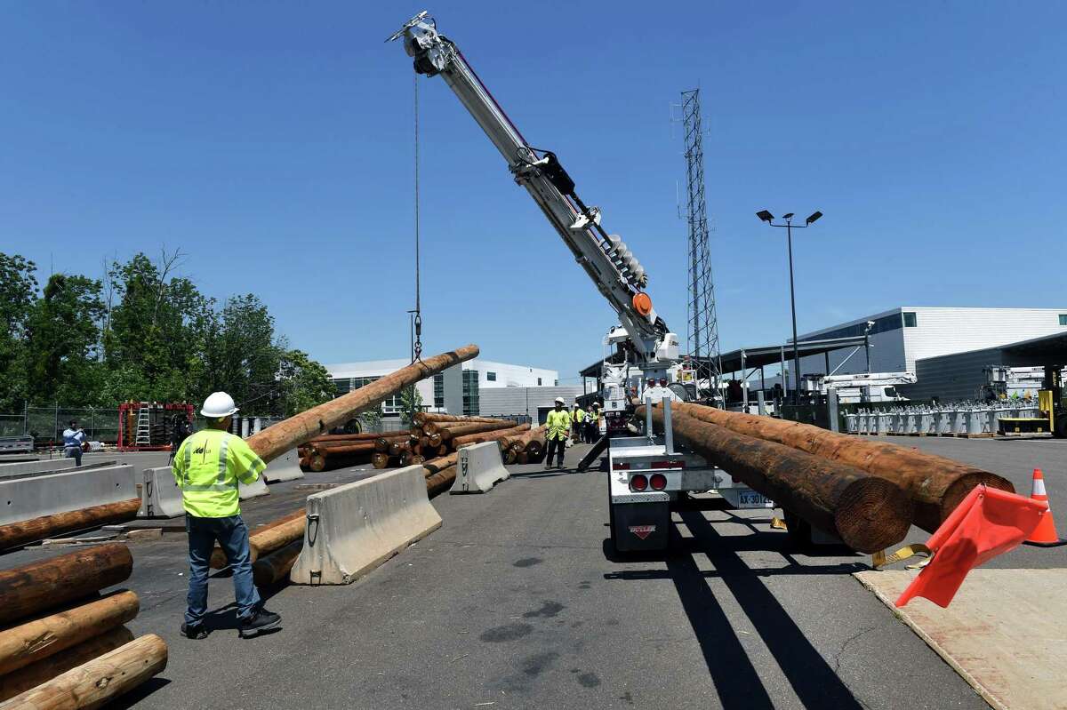 United Illuminating workers demonstrate the loading of utility poles on a trailer at the United Illuminating Operations Center in Orange on June 18, 2021.