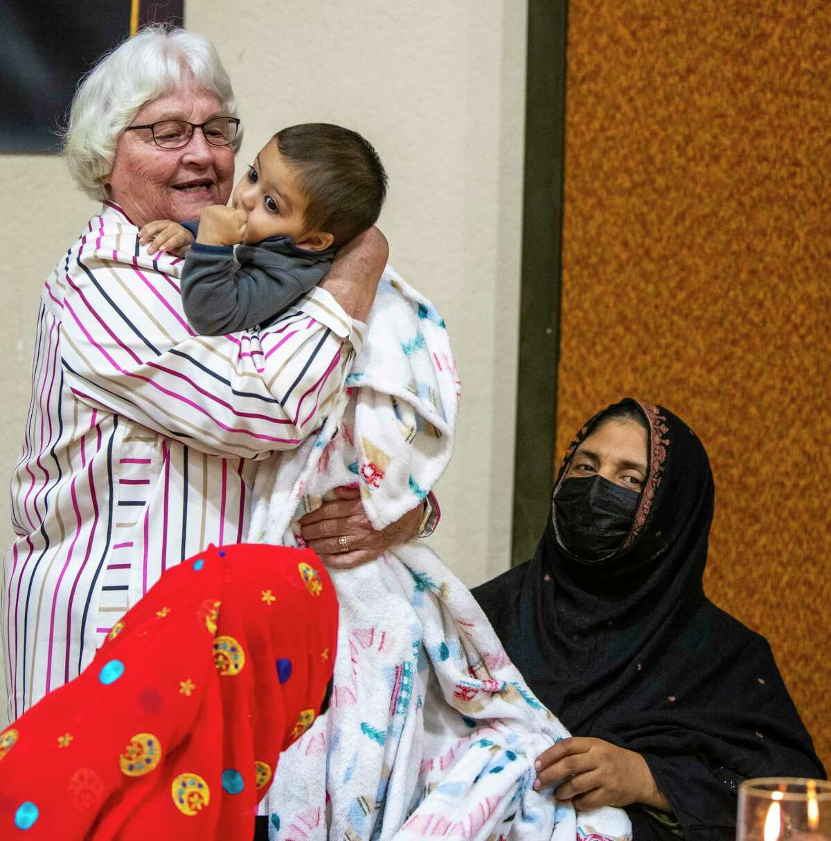 Anne Ziegler interacts with members of the Afghan community attending an interfaith Thanksgiving dinner on Sunday. The event was attended by Ethiopian, Congolese and several Afghan refugee families at Cross Roads Church in Windcrest.