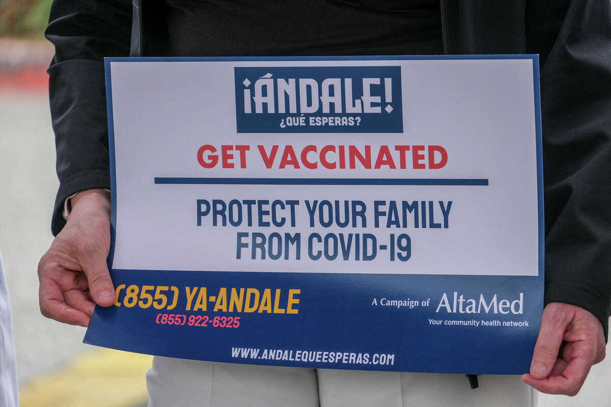 A medical worker holds a sign at AltaMed Medical clinic in Los Angeles, urging people to update their COVID shots as the fall/winter season arrives.