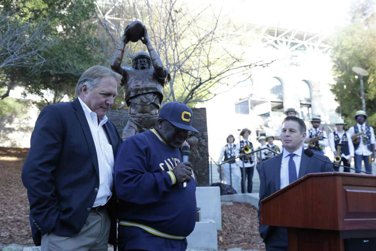 Kevin Moen, left, and Ahmad Anderson take a moment of silence on Friday, Nov. 18, 2022, to remember Dwight Garner, running back in the 1982 Big Game, after learning of his death. Moen and Anderson participated in a ceremony outside Memorial Stadium in Berkeley, Calif., to mark the 40th anniversary of Moen’s touchdown to cap The Play, the Bears’ five-lateral kickoff return to beat Stanford 25-20 in the 1982 Big Game. Roxy Bernstein, a Cal alum and broadcaster for ESPN and Pac-12 Network, is at the podium.
