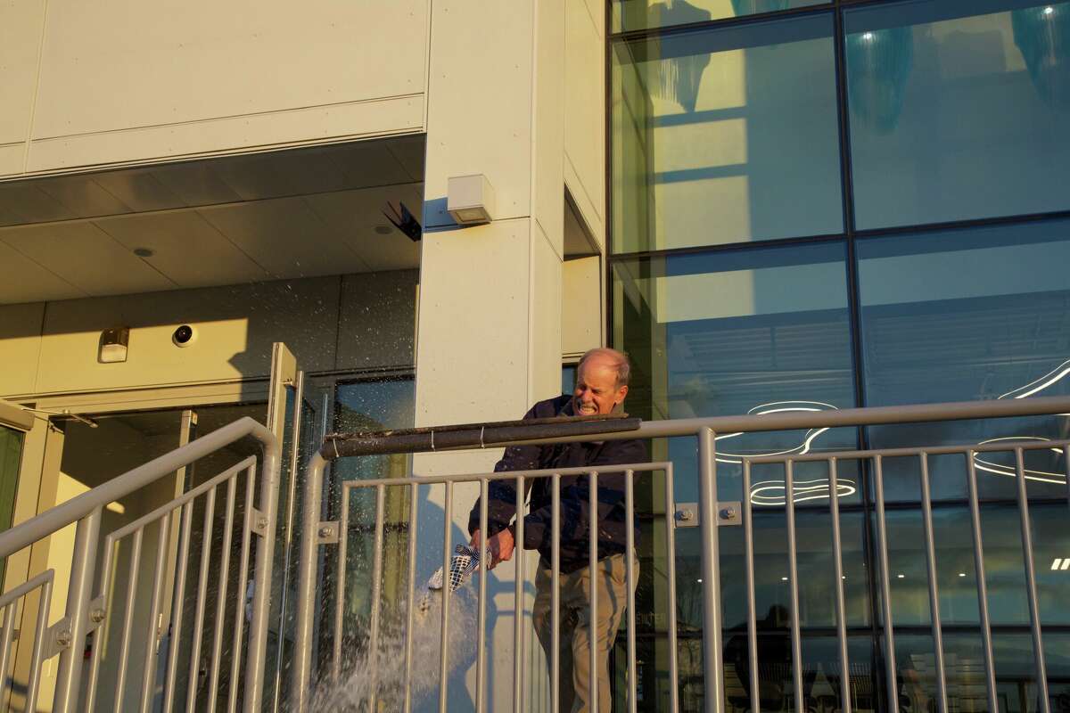 SoundWaters Board Chair, Doug Bora, in true maritime fashion, officially launches the Cohen SoundWaters Harbor Center by smashing a bottle of champagne on the front of the building in a ceremony at Boccuzzi Park on Nov. 17.