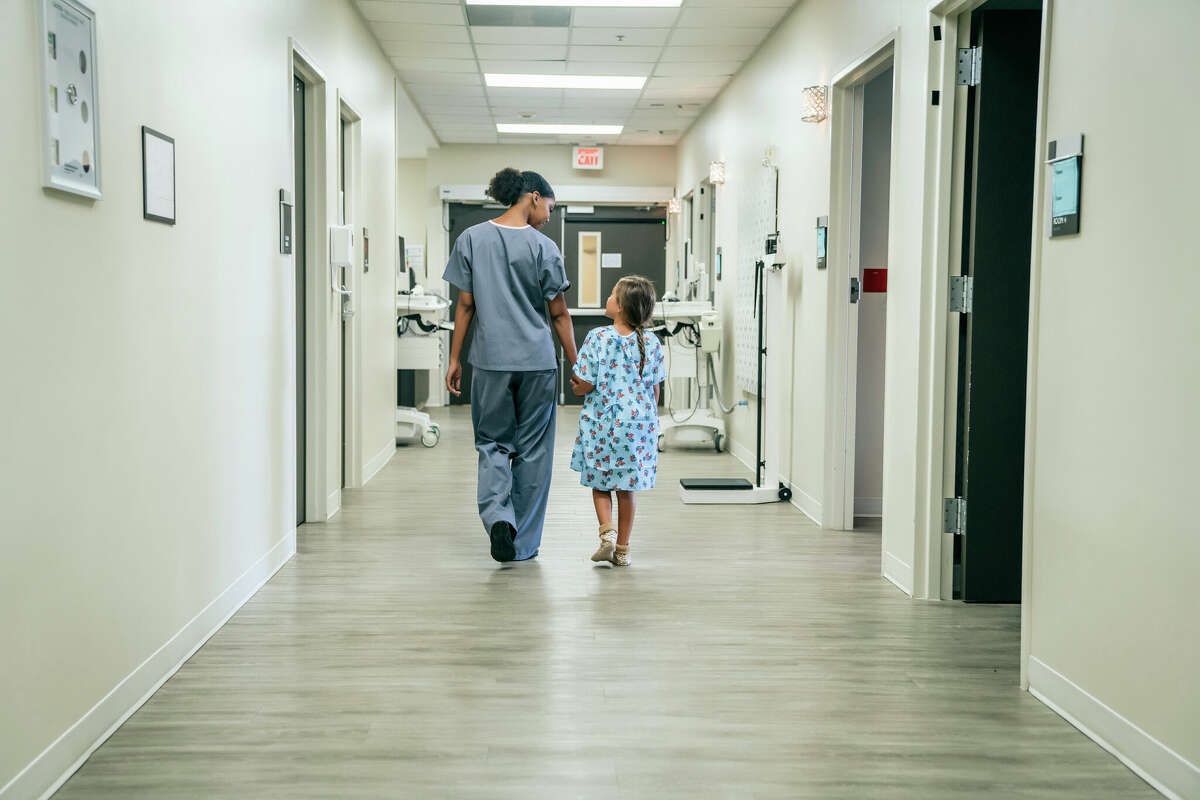 A nurse walking with a pediatric patient in a hospital 