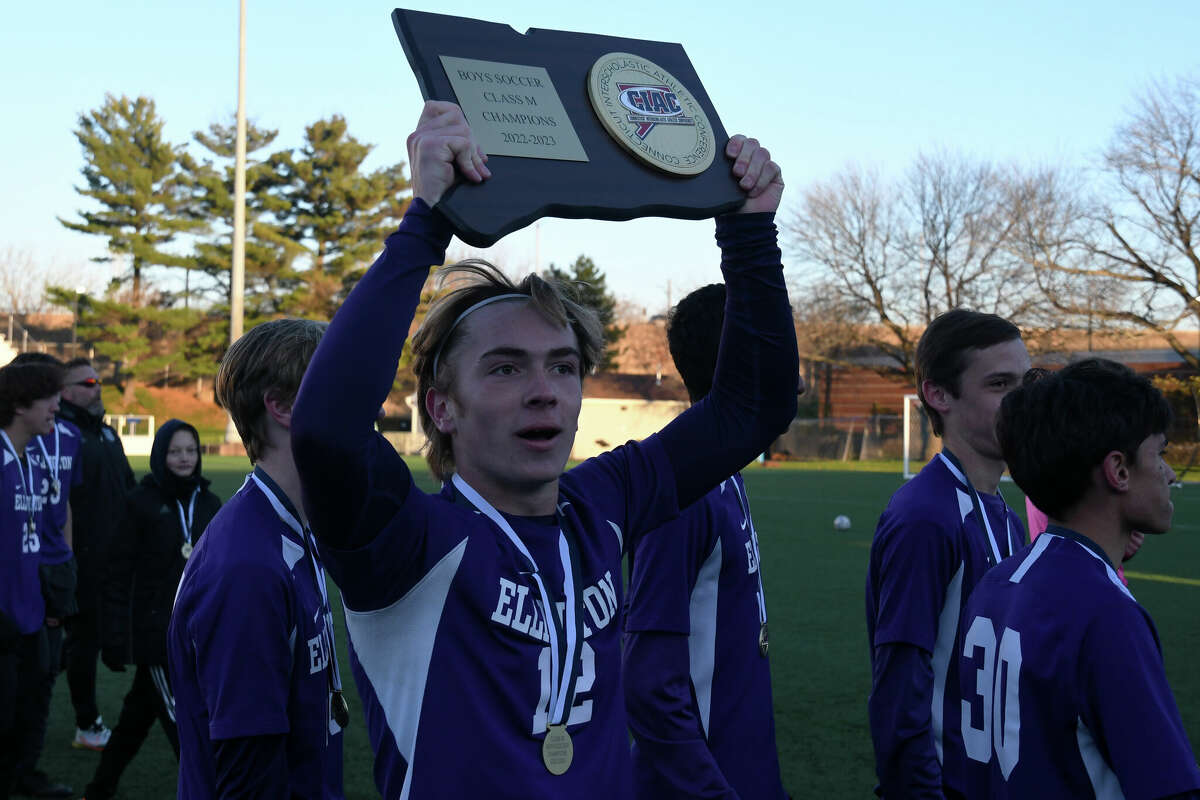 Ellington's Nicholas Elsass holds up the championship plaque after the Class M boys soccer finals between Ellington and Weston at Trinity Health Stadium on Saturday, Nov. 19, 2022.