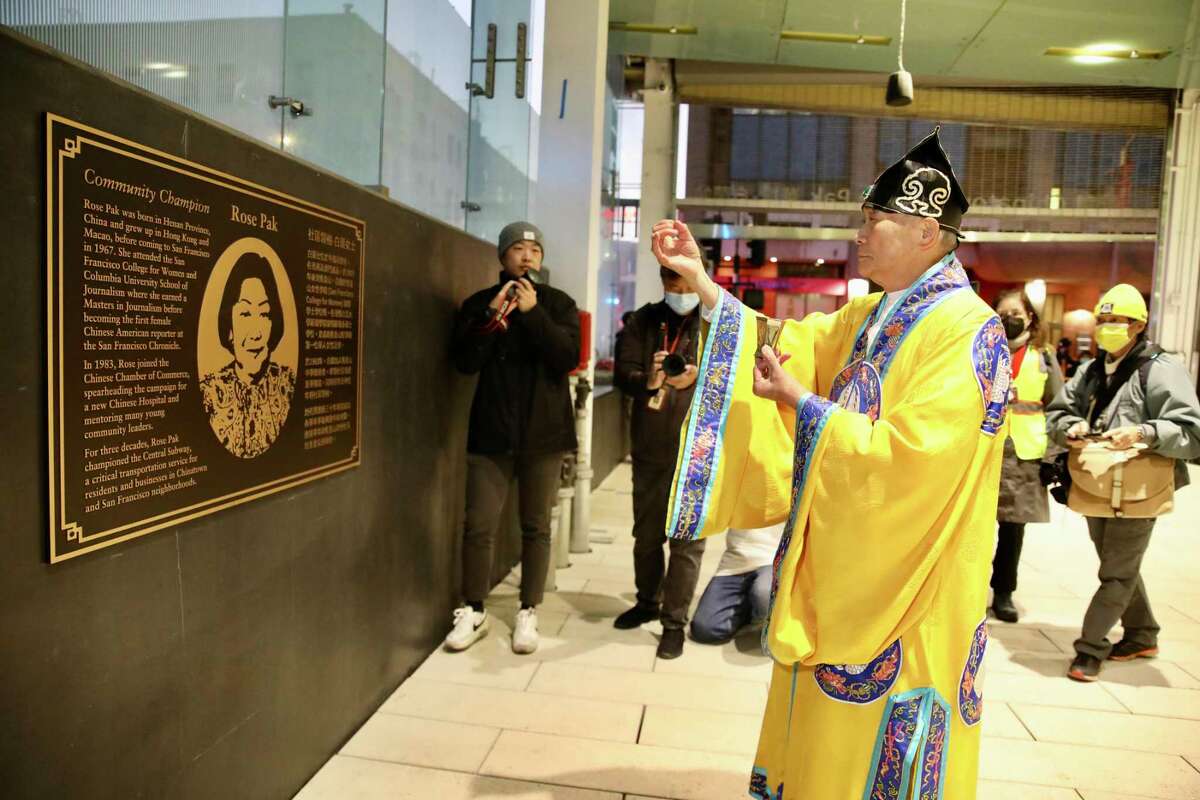 Rev.  Norman Fong blesses a plaque commemorating Rose Pak, a driving force behind the creation of the Central Subway.