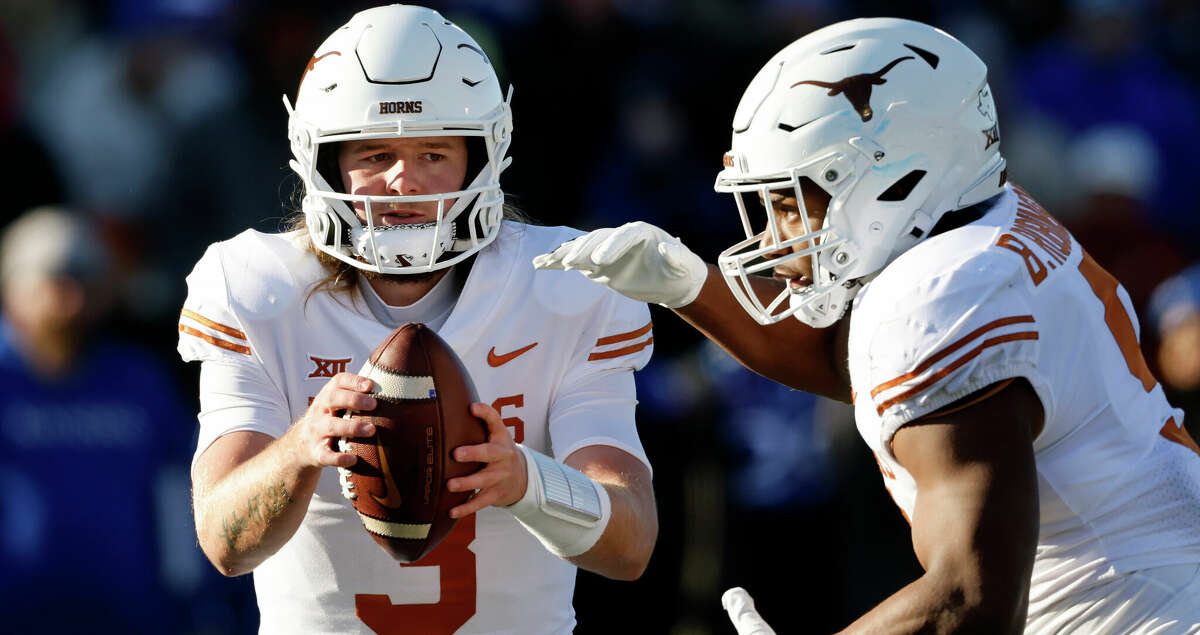 Texas quarterback Quinn Ewers, left, fakes a handoff to running back Bijan Robinson, right, during the second quarter of an NCAA college football game against Kansas on Saturday, Nov. 19, 2022, in Lawrence, Kan. (AP Photo/Colin E. Braley)