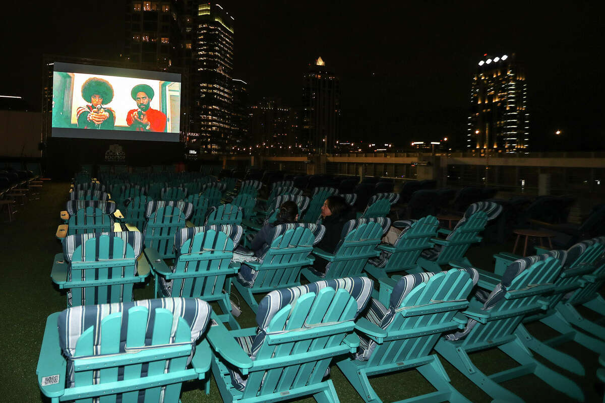 Previews play on the screen as moviegoers start to fill in before a showing of "Top Gun: Maverick" at Rooftop Cinema Club 