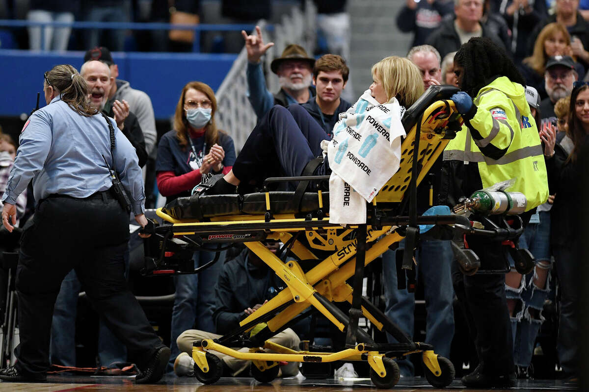 Associate Head Coach Chris Dailey is taken off the basketball court on a stretcher before an NCAA basketball game against North Carolina State, Sunday, Nov. 20, 2022, in Hartford, Conn. Dailey experienced a medical emergency during the national anthem. 