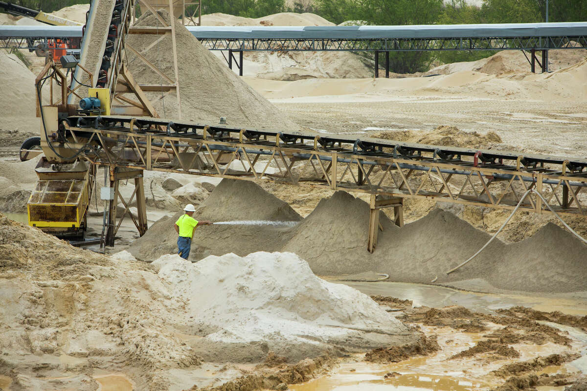 A worker sprays down piles of sand at the Superior Silica Sands sand mine on Tuesday, March 28, 2017, in Kosse. Demand for sand is surging as oil and gas production in the Permian Basin is booming again. Not only is the need for more sand on the rise with the increase in oil and gas production in West Texas, but much more sand is being pumed into each well now withi the emerging thesis that more sand equals more oil extracted. ( Brett Coomer / Houston Chronicle )