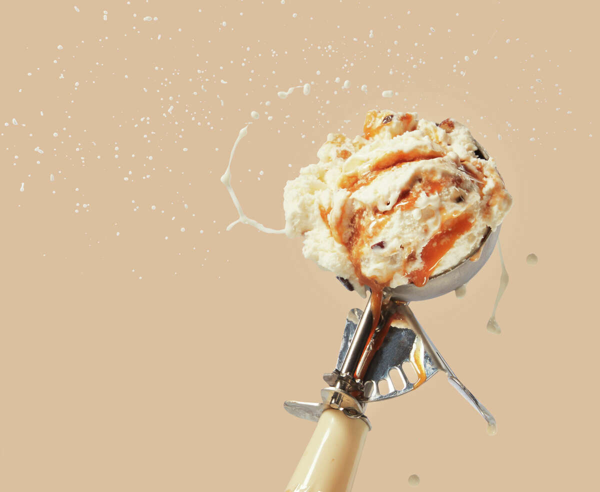 A salted caramel scoop of ice cream flinging from scooper.