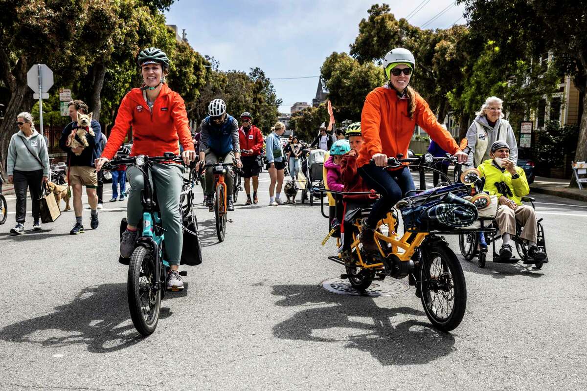 People walk and cycle along Lake Street during a community parade in support of the Slow Street in the Richmond neighborhood of San Francisco this past April.