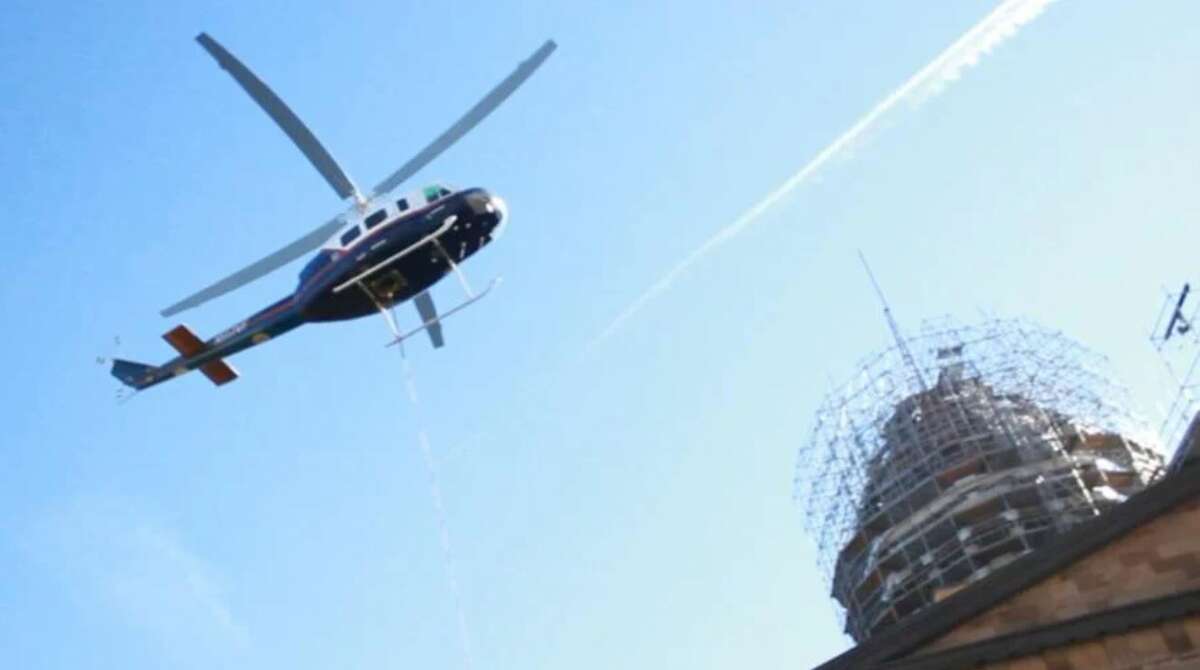 A helicopter prepares to remove the flagpole atop the Old State Capitol in Springfield on Monday.   