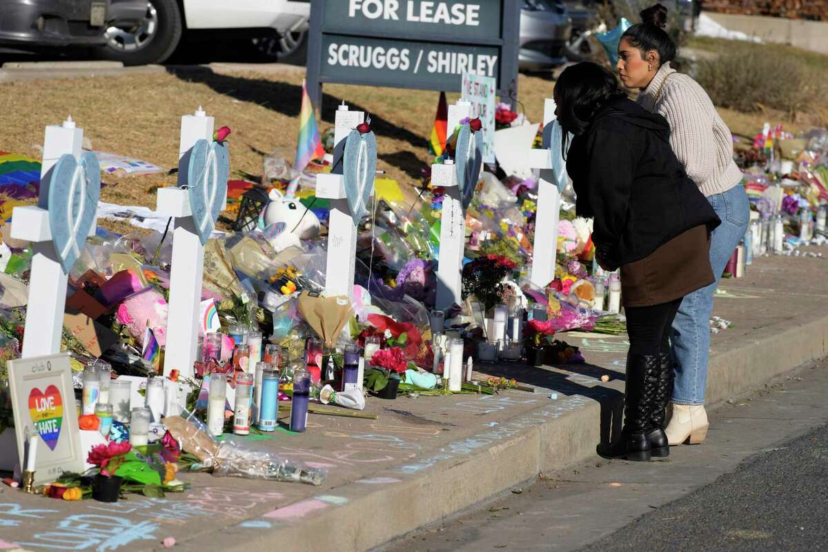 Mourners stand along the makeshift memorial to the victims of a weekend mass shooting at a nearby gay nightclub on Tuesday, Nov. 22, 2022, in Colorado Springs, Colo. Anderson Lee Aldrich opened fire at Club Q, in which five people were killed and others suffered gunshot wounds before patrons tackled and beat the suspect into submission. (AP Photo/David Zalubowski)