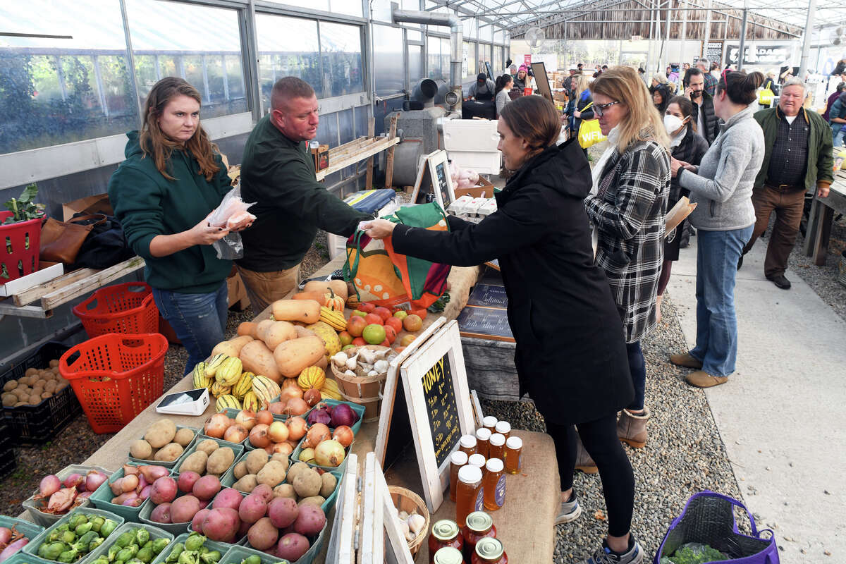 Kelly Sullivan and Mark Maynard, of Ox Hollow Farm in Roxbury, help customers during the weekly winter farmers’ market in Westport, Conn. Nov. 22, 2022.