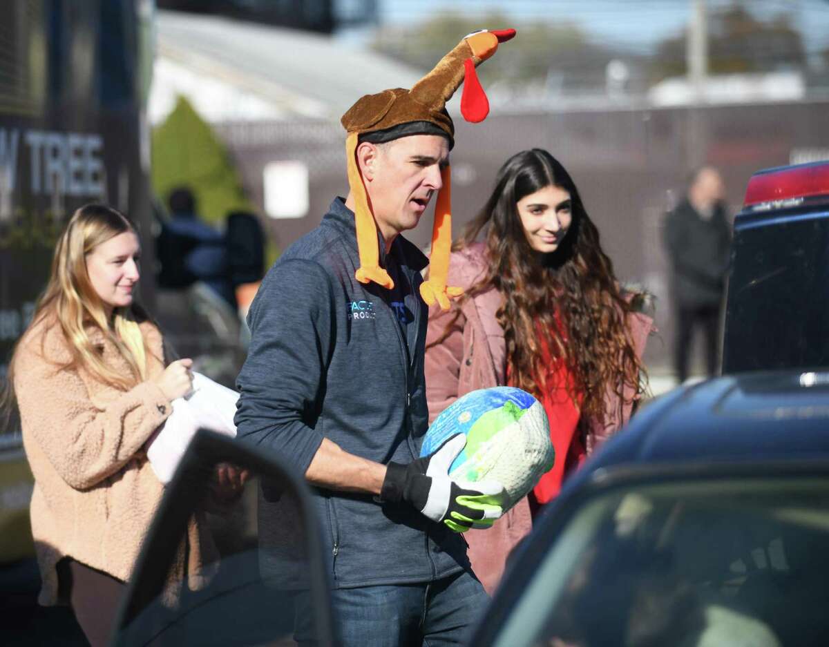 Jeff Boulanger, a volunteer with FactSet, loads a turkey into a car during the Person to Person turkey distribution at the East Norwalk Association Library in Norwalk, Conn. Tuesday, Nov. 22, 2022. The Person to Person distributed a total of 1,200 full Thanksgiving dinners, each including a turkey or chicken and several side dishes, between the three locations in Stamford, Darien, and Norwalk.