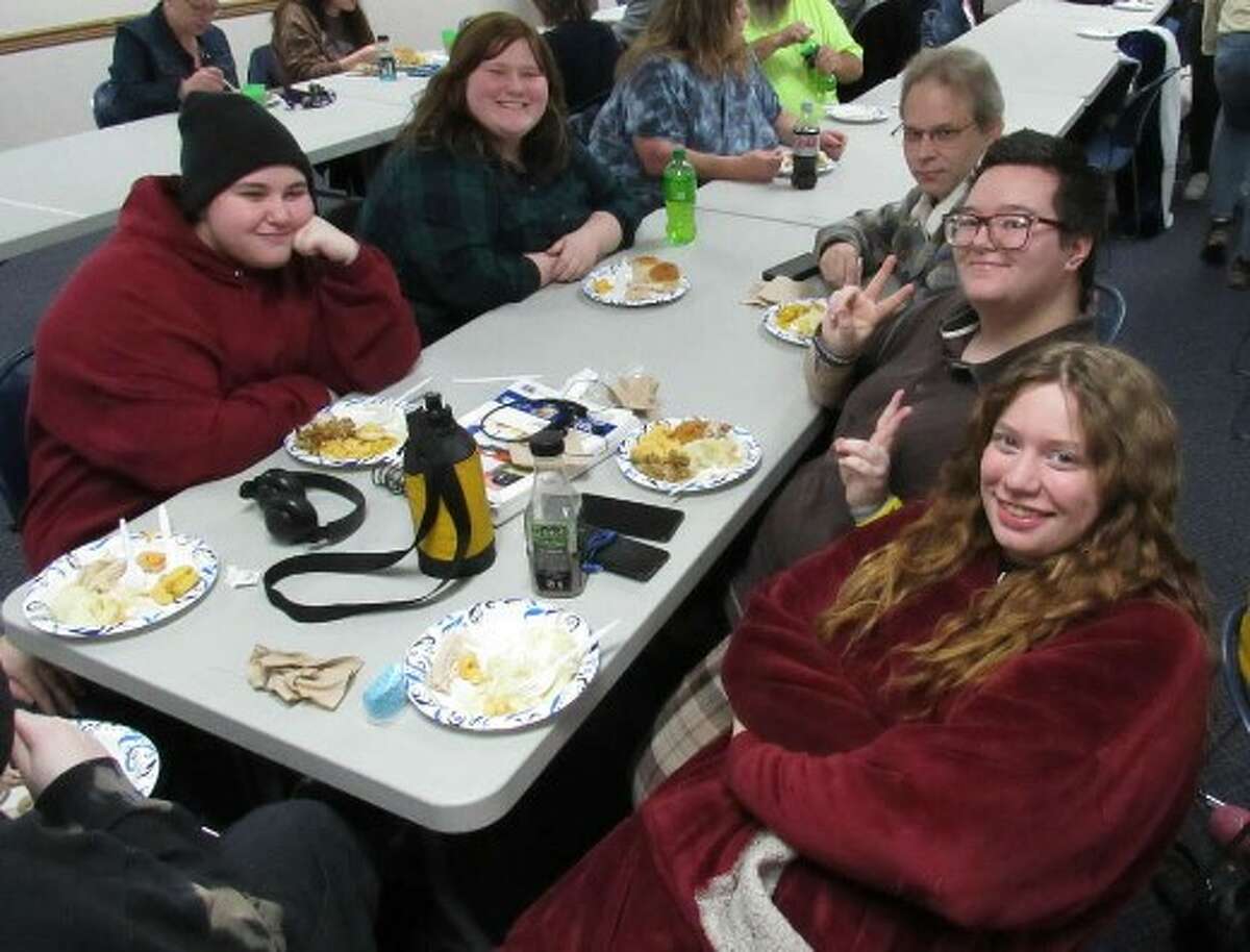 Alternative student Jace Bunker holds up two peace signs at Thanksgiving lunch, where she sits beside student Emalee Brown, for Academic and Career Education Academy (ACEA) on Nov. 22, 2022 in Midland. 