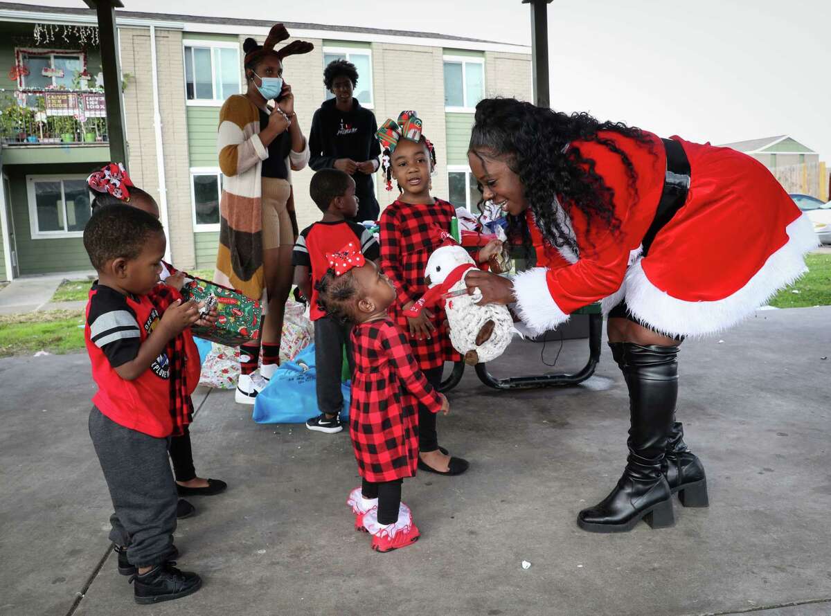 Wanda Hubbard, right, gives a stuffed owl to Aaliyah Washington, 1, during a Christmas celebration Saturday, Dec. 25, 2021, at the Garden City Apartments in Houston. Volunteers handed out holiday dinners and toys to families in the complex.