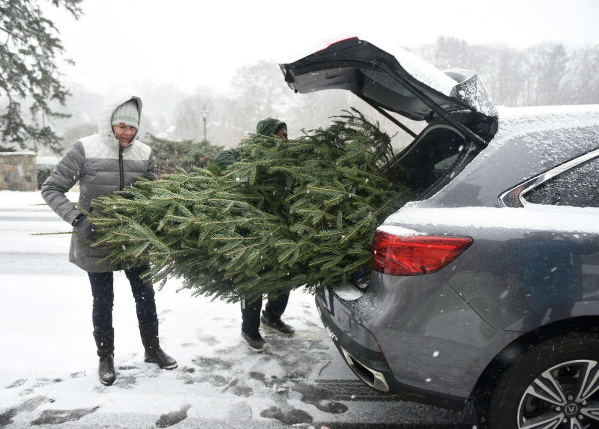 Volunteer Leslie Vandermeer helps put a tree in the trunk of a car at the Tree & Wreath Sale at First Congregational Church of Old Greenwich in Old Greenwich, Conn. Sunday, Dec. 1, 2019. The sale will return this weekend and the first weekend of December but supplies are limited so people are urged to act quickly.
