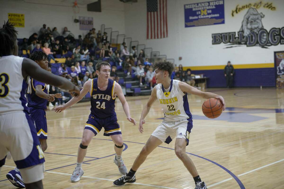 Midland High's London Rickett dribbles while being guarded by Abilene Wylie's Martin Marshall during a Nov. 22 basketball game at the MHS gym. 