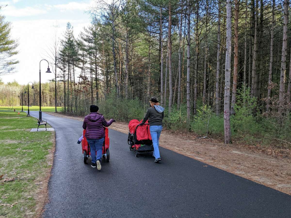 Miriam Silva, left, and MacKensi Montanez push strollers on a path through Clifton Park's new park.