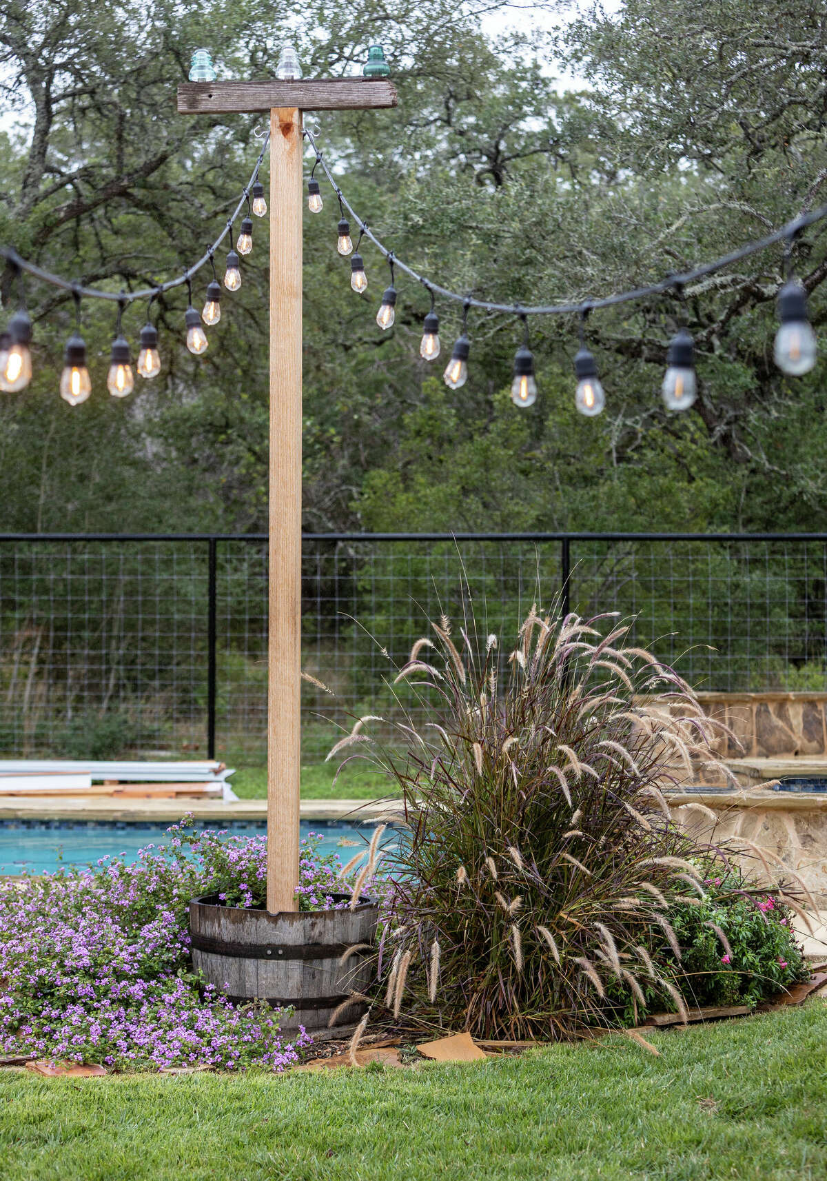 Strings of Edison-style lights run from the house to a pair of posts near the pool.  These posts are topped with several vintage glass insulators.
