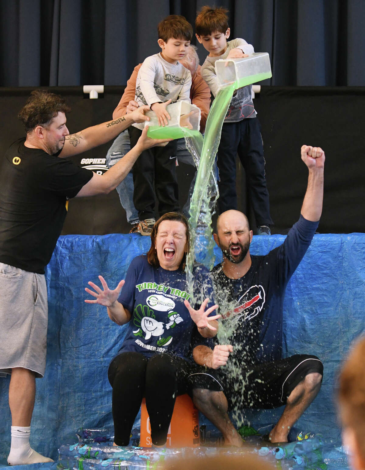 Principal Kathleen Ramirez and physical education teacher Dan Taylor get slimed by fellow gym teacher Pat Prisinzano, left, and students Sam and Hugo Kantor during the Neighbor to Neighbor food drive celebration at North Mianus School in the Riverside section of Greenwich, Conn. Wednesday, Nov. 23, 2022. North Mianus students and faculty donated thousands of pounds of food to local food pantry Neighbor to Neighbor. To celebrate, students played in a cornhole championship match and "slimed" their teachers.