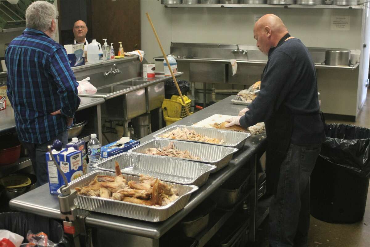 Jim Naffie (right) tends to the turkey Wednesday in preparation of the 48th annual Bette J. Naffie Memorial Thanksgiving Dinner while Michael Naffie (left) and Mike Gielcyzk look on.