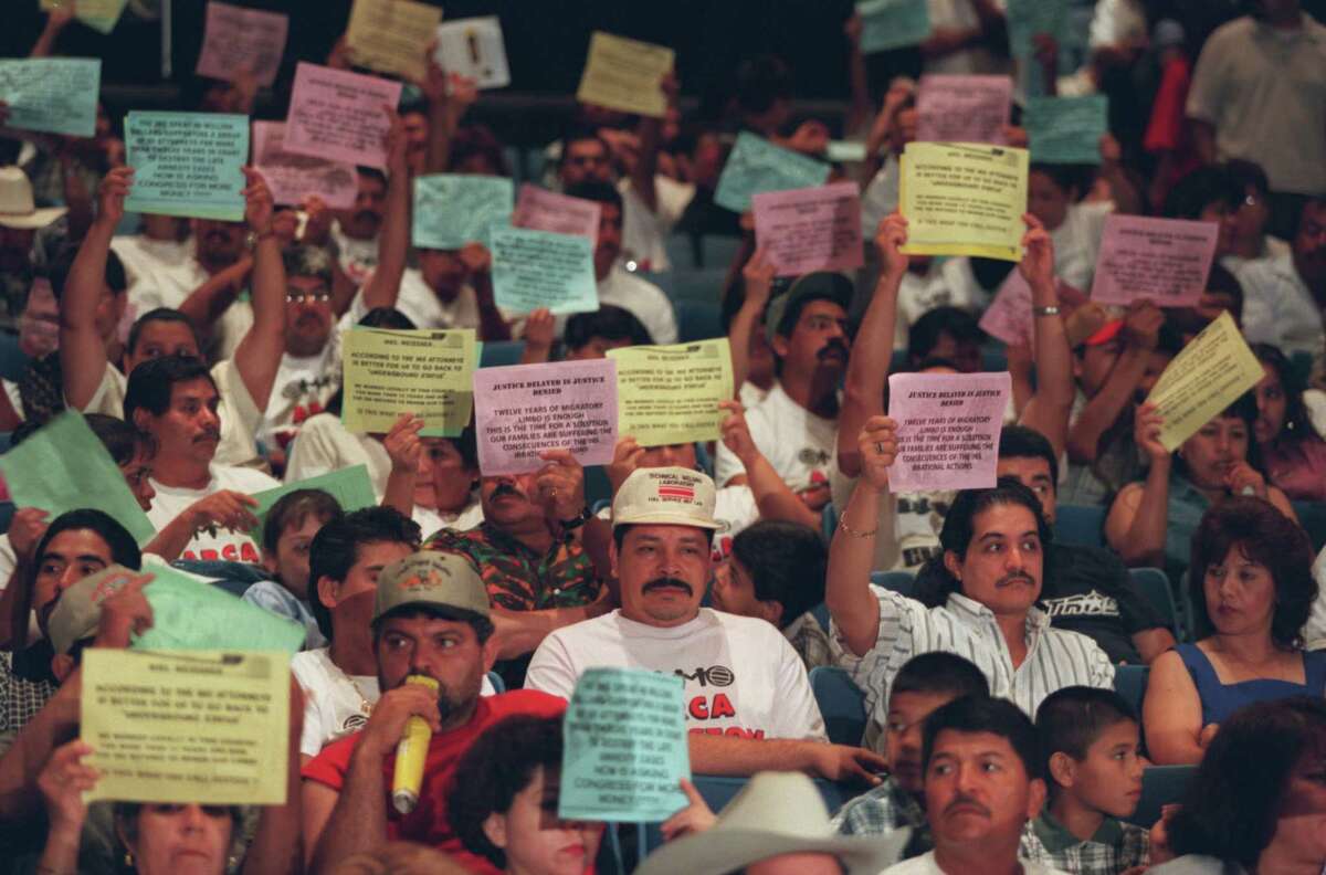 Members and supporters of the American Citizenship and Residency Association hold signs during a town hall meeting with Immigration and Naturalization Services Commissioner Doris Meissner to demonstrate for the reopening of the amnesty application process for the 350,000 immigrants who delayed filing due to of a misinterpretation of the Immigration Reform and Control Act of 1986. The town meeting took place at the National Council of La Raza Conference held at the George R. Brown Convention Center, Houston on July 25, 1999.