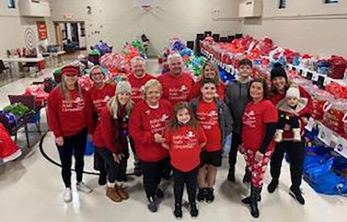 Volunteers and family members pose for a photo as they prepare gifts to be delivered to children in the Granite City area through the Billie’s Kids Christmas charity.