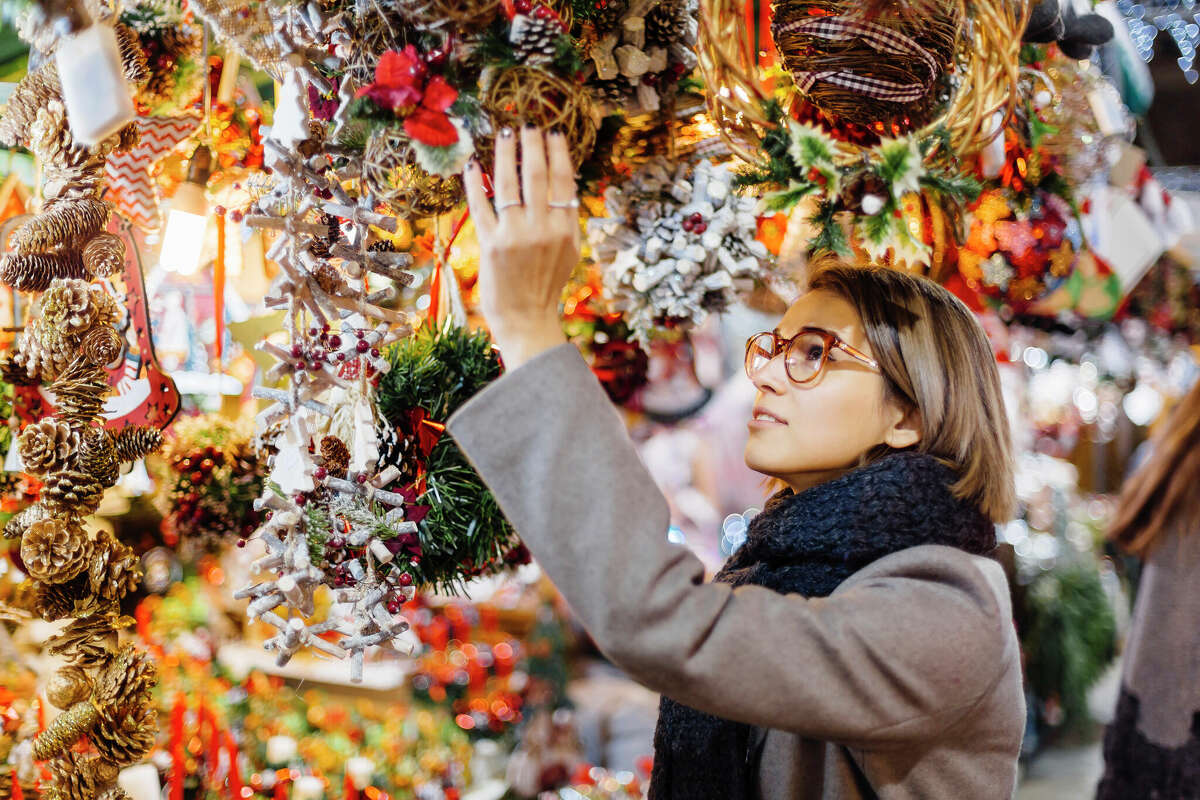 A woman looking at Christmas decorations at a holiday market 