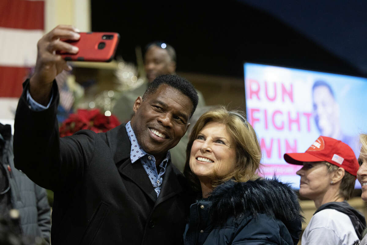 Republican Senate nominee Herschel Walker takes a photo with a supporter during a rally on November 21, 2022 in Milton, Georgia. Walker faces incumbent Sen. Raphael Warnock (D-GA) in a runoff election on December 6th.