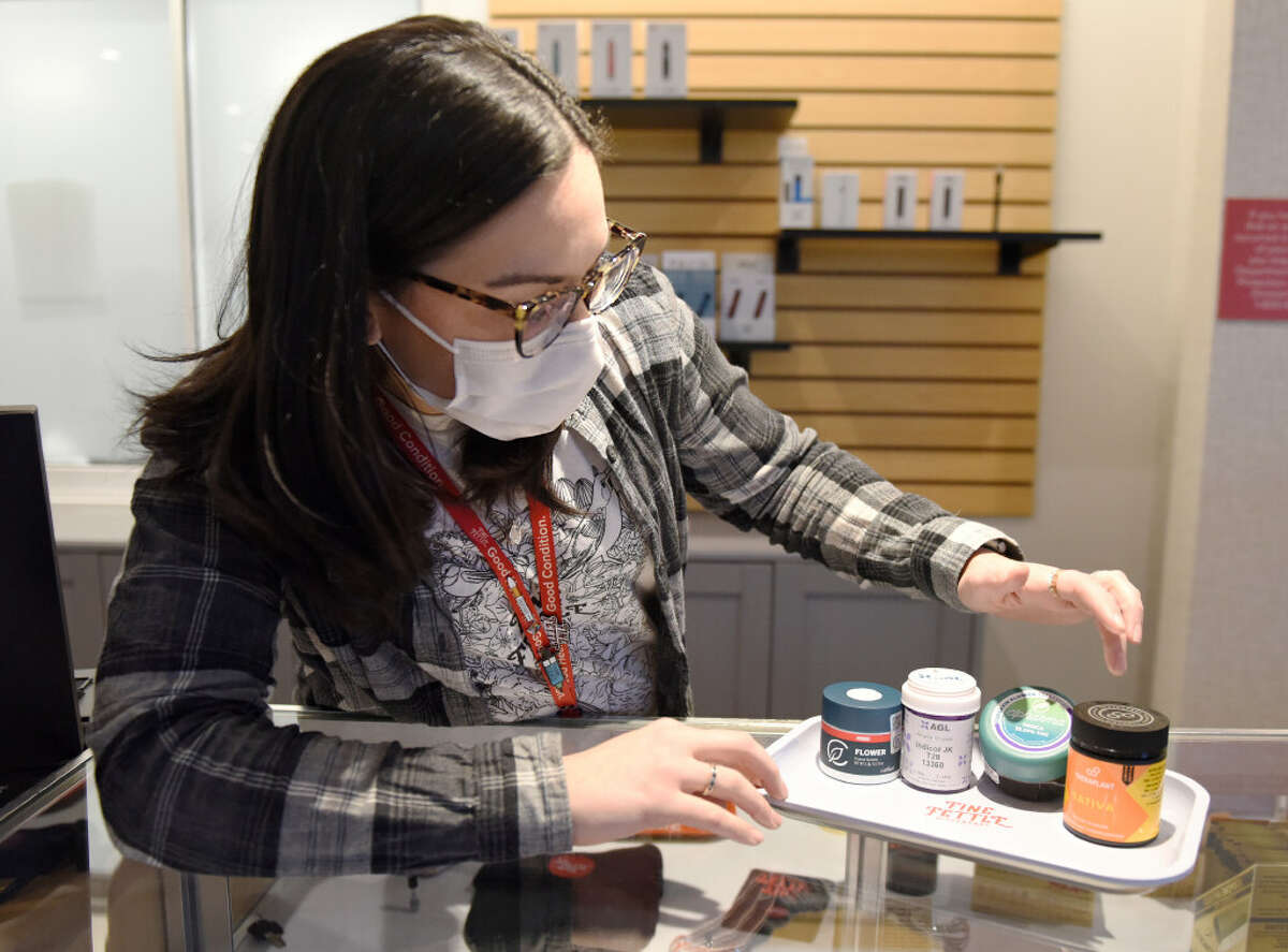 Assistant manager Marion Baxter shows cannabis from the four Connecticut growers at Fine Fettle medical marijuana dispensary in Stamford, Conn., on Monday, Feb. 21, 2022.