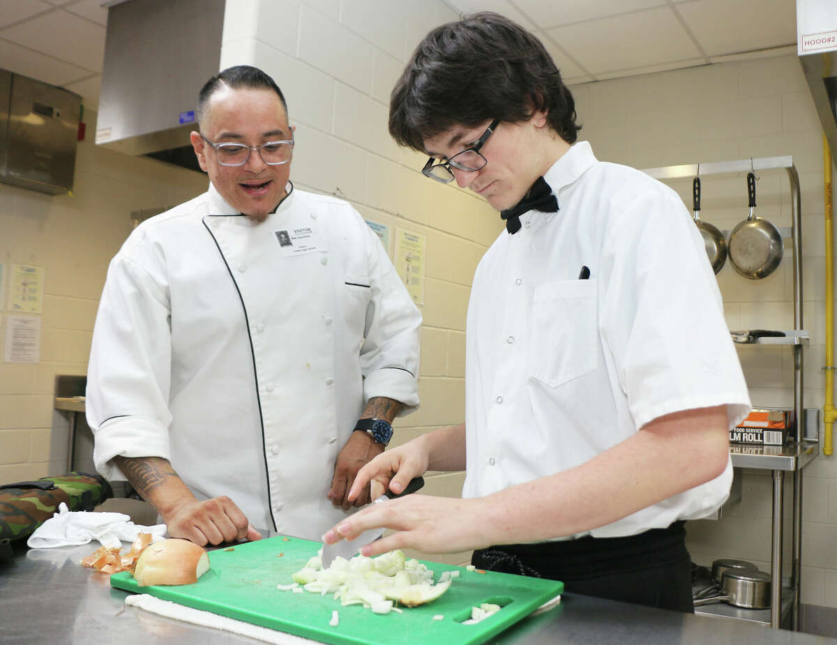 Chef Abe Sanchez watches carefully as Crosby High School senior William Fininis use his learned knife skills to chop up an onion. He wants a career in the food industry and may start in the Armed Forces serving either the Marines or Army soldiers.