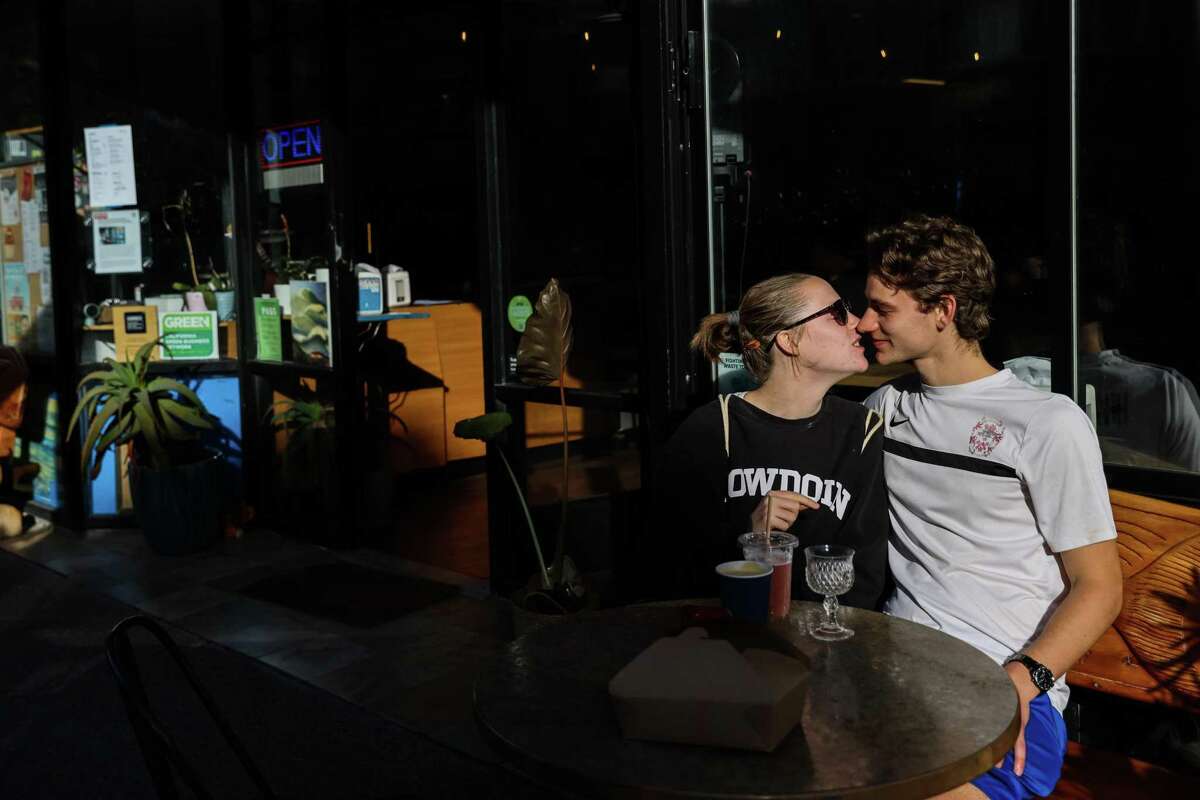 爱丽丝·霍金斯和艾登·洛滕在旧金山的海洋海滩咖啡馆外用餐时亲吻。