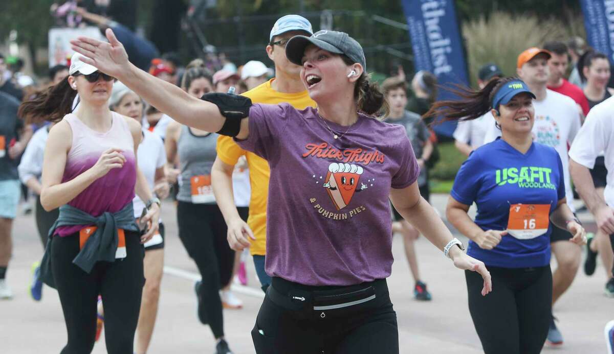 A runner blows a kiss to family as she takes part in the YMCA’s annual Run Thru the Woods race on Thanksgiving Day, Thursday, Nov. 24, 2022, in The Woodlands.